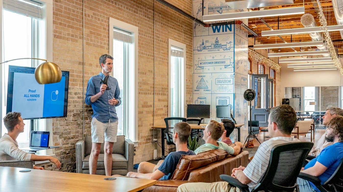 A team leader presenting to colleagues in a bright, collaborative workspace